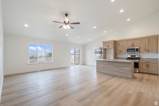 kitchen with open floor plan, appliances with stainless steel finishes, ceiling fan, and a sink