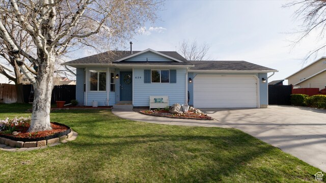 ranch-style house featuring a front yard, an attached garage, fence, and concrete driveway