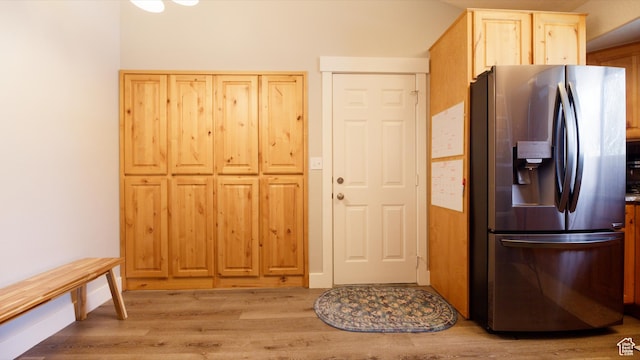 kitchen with light wood-type flooring, stainless steel refrigerator with ice dispenser, and light brown cabinets