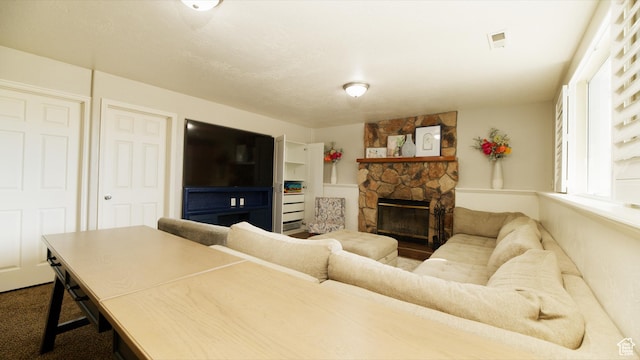 living area with visible vents and a stone fireplace