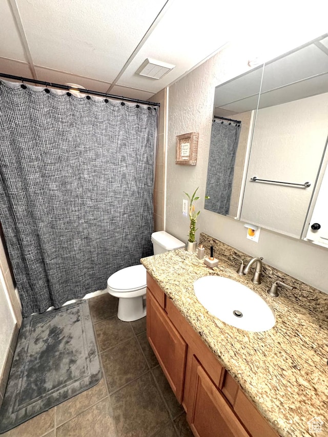 bathroom featuring a shower with curtain, toilet, a textured wall, vanity, and tile patterned floors