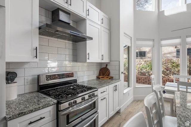 827 E 1070 S, St George, UT 84790 - kitchen featuring white cabinets, wall chimney range hood, range with two ovens, light stone countertops, and light wood-style flooring