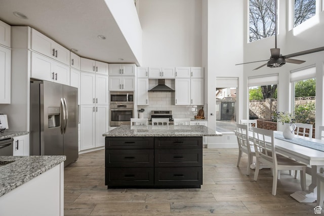 827 E 1070 S, St George, UT 84790 - kitchen featuring light wood-type flooring, wall chimney range hood, white cabinets, and stainless steel appliances