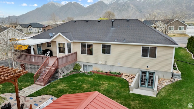 back of property featuring a deck with mountain view, stairway, french doors, and a lawn