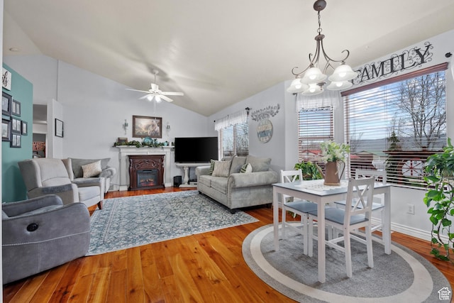 living room featuring wood finished floors, a glass covered fireplace, lofted ceiling, and a healthy amount of sunlight