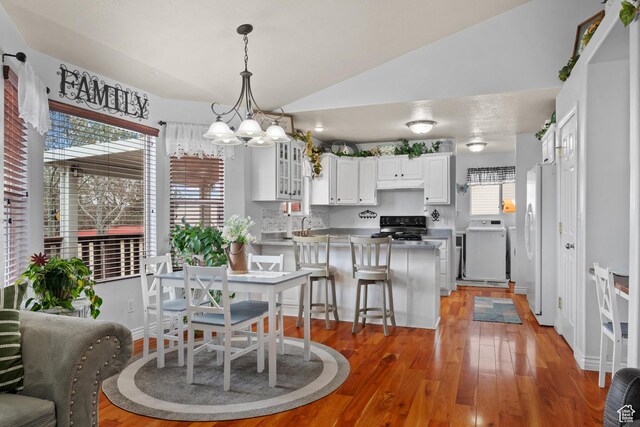 dining space featuring light wood finished floors, vaulted ceiling, and an inviting chandelier