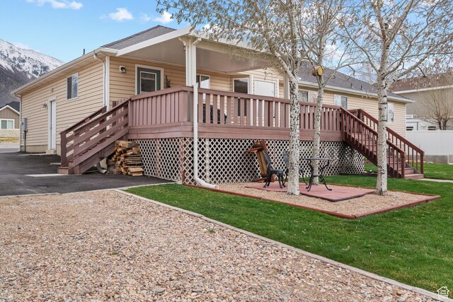 back of property featuring a deck with mountain view, a lawn, and stairs