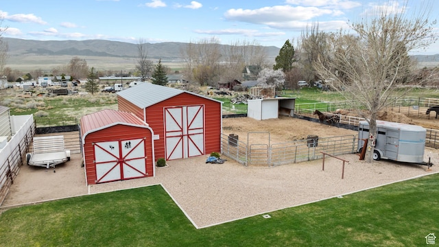 view of barn featuring a yard, a mountain view, fence, and an exterior structure