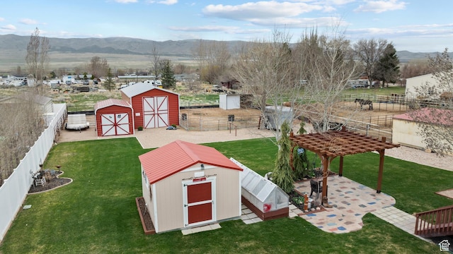 view of yard with an outbuilding, a mountain view, a fenced backyard, and a storage unit