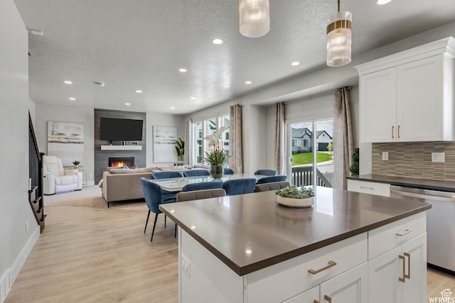 kitchen featuring tasteful backsplash, a textured ceiling, dark countertops, light wood finished floors, and dishwasher