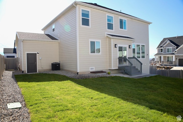 rear view of house featuring central air condition unit, a yard, and fence