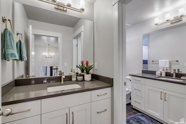 bathroom with a sink, tile patterned floors, two vanities, and a chandelier