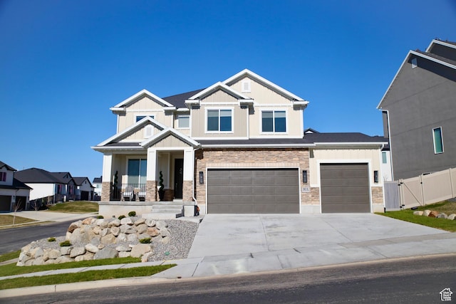 craftsman-style home featuring board and batten siding, fence, stone siding, a gate, and concrete driveway