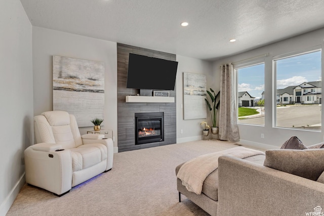 living room with baseboards, a tiled fireplace, a textured ceiling, carpet floors, and recessed lighting