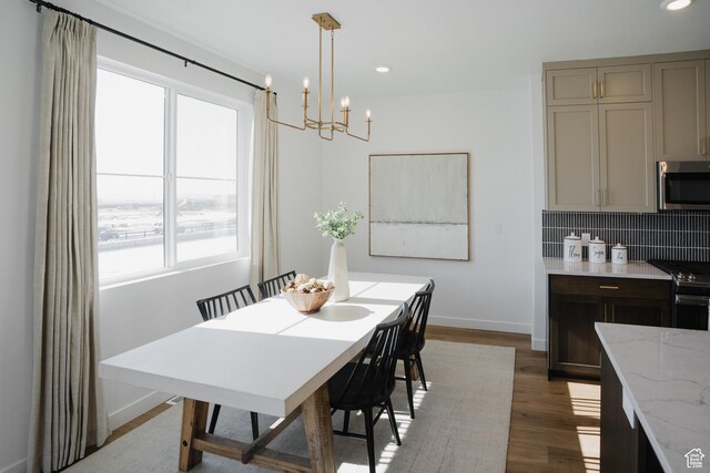 dining space featuring a chandelier, recessed lighting, baseboards, and wood finished floors