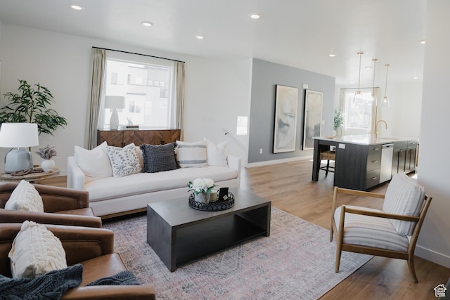 living area featuring baseboards, light wood finished floors, and recessed lighting