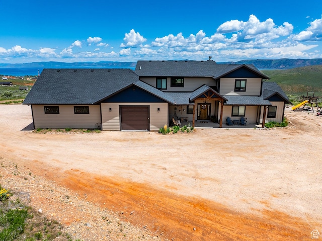 3525 S Sweetwater Pkwy, Garden City, UT 84028 - view of front facade featuring driveway, a garage, a shingled roof, a mountain view, and covered porch