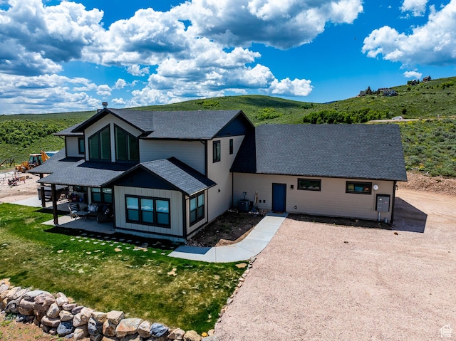 3525 S Sweetwater Pkwy, Garden City, UT 84028 - view of front of house with a shingled roof, a patio area, board and batten siding, and a front lawn