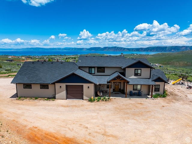 3525 S Sweetwater Pkwy, Garden City, UT 84028 - view of front of home featuring driveway, a shingled roof, an attached garage, and a water and mountain view