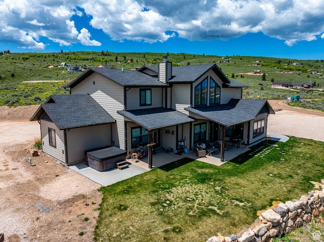 3525 S Sweetwater Pkwy, Garden City, UT 84028 - back of house with a hot tub, a shingled roof, a patio, and a chimney