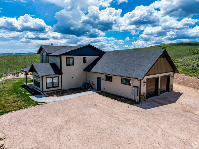 3525 S Sweetwater Pkwy, Garden City, UT 84028 - view of front of home with driveway, roof with shingles, stone siding, and a garage