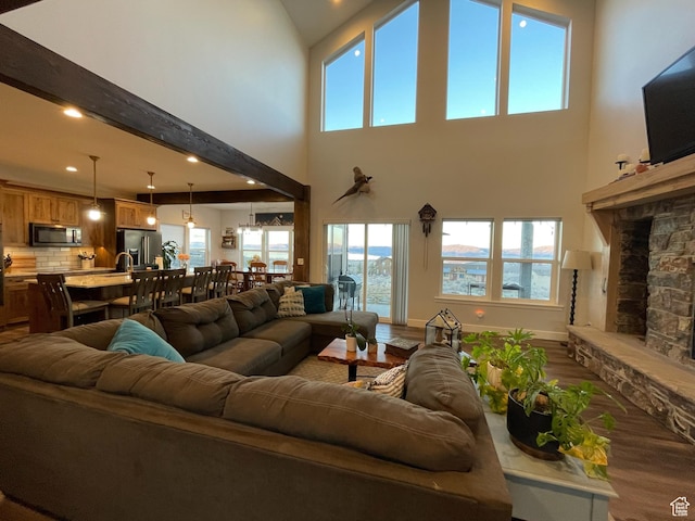 3525 S Sweetwater Pkwy, Garden City, UT 84028 - living room with wood finished floors, a stone fireplace, a high ceiling, recessed lighting, and plenty of natural light