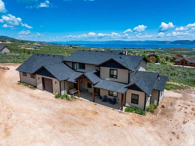 3525 S Sweetwater Pkwy, Garden City, UT 84028 - view of front of property with a shingled roof, a garage, a mountain view, and dirt driveway