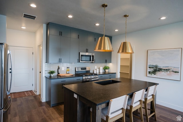 kitchen with dark countertops, dark wood-type flooring, visible vents, decorative backsplash, and stainless steel appliances