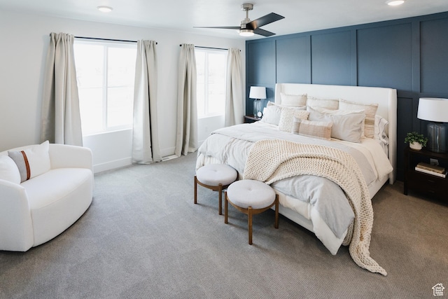 bedroom featuring a decorative wall, baseboards, a ceiling fan, and light carpet