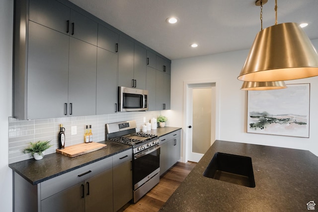 kitchen featuring tasteful backsplash, dark wood-style flooring, recessed lighting, appliances with stainless steel finishes, and a sink