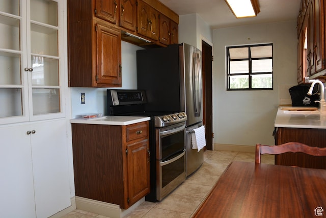 418 N 9th St, Montpelier, ID 83254 - kitchen with light tile patterned floors, a sink, light countertops, brown cabinets, and range with two ovens