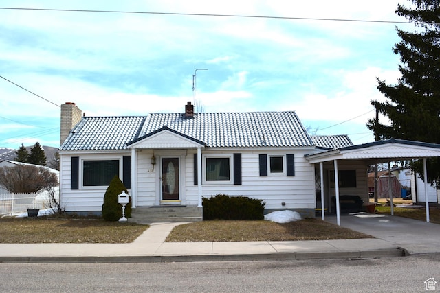 view of front of property with a carport, driveway, a chimney, and a tile roof