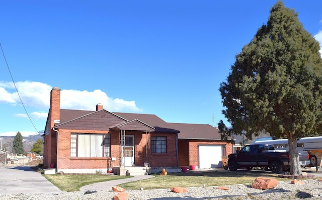 view of front of property with brick siding, a front yard, an attached garage, and a chimney