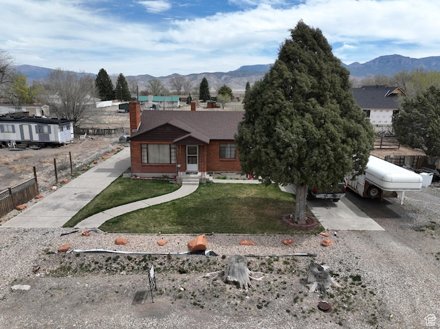255 S Center St, Circleville, UT 84723 - view of front of home with a mountain view, a chimney, fence, brick siding, and a front lawn