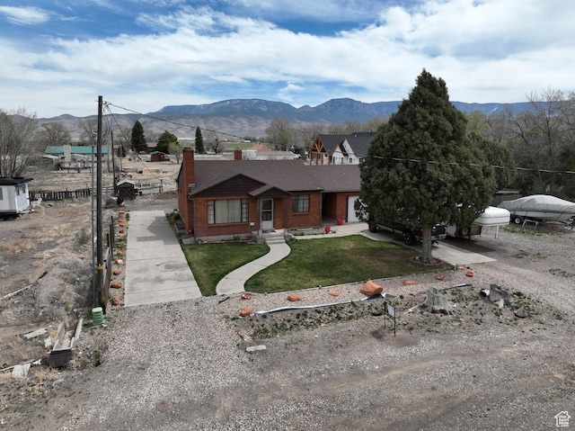 255 S Center St, Circleville, UT 84723 - view of front facade with brick siding, a chimney, a mountain view, and a front lawn