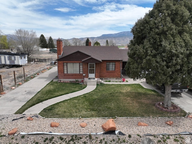 255 S Center St, Circleville, UT 84723 - view of front of home featuring a mountain view, a chimney, a front lawn, brick siding, and a shingled roof
