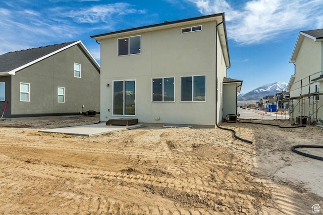 back of property with central AC unit, a mountain view, visible vents, a patio, and stucco siding