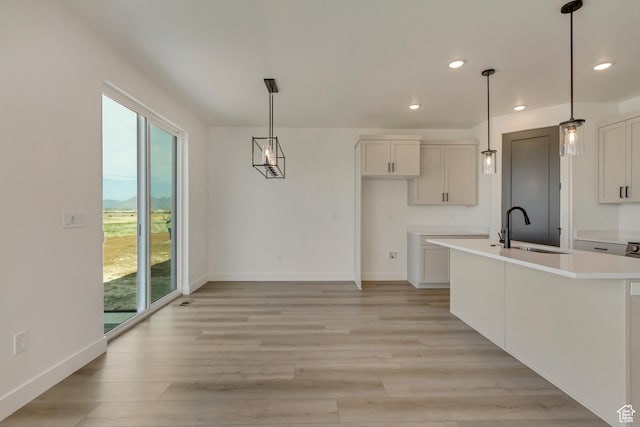 kitchen with light wood-style flooring, a sink, baseboards, and recessed lighting