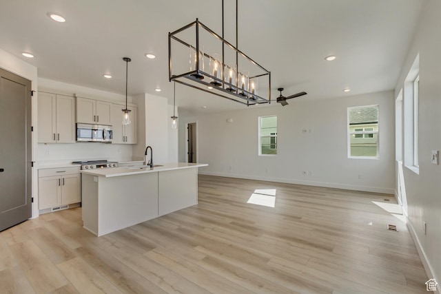 kitchen with a sink, light wood-type flooring, a ceiling fan, stainless steel microwave, and recessed lighting
