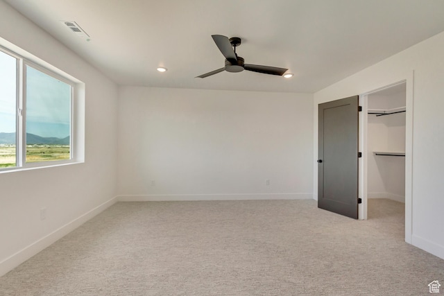 unfurnished bedroom featuring baseboards, visible vents, recessed lighting, light colored carpet, and a walk in closet