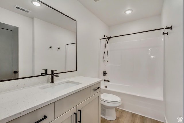 bathroom with wood finished floors, vanity, washtub / shower combination, toilet, and visible vents