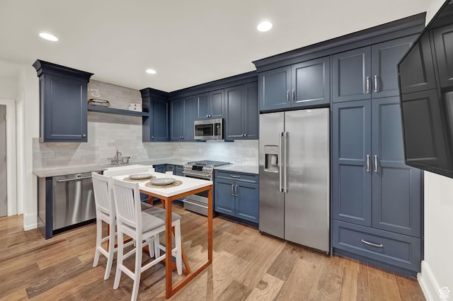 kitchen featuring stainless steel appliances, light wood finished floors, and decorative backsplash