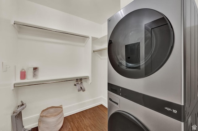 laundry room with baseboards, stacked washer / drying machine, laundry area, and wood finished floors