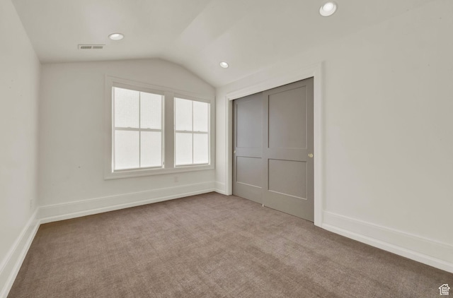 unfurnished bedroom featuring baseboards, recessed lighting, visible vents, lofted ceiling, and carpet