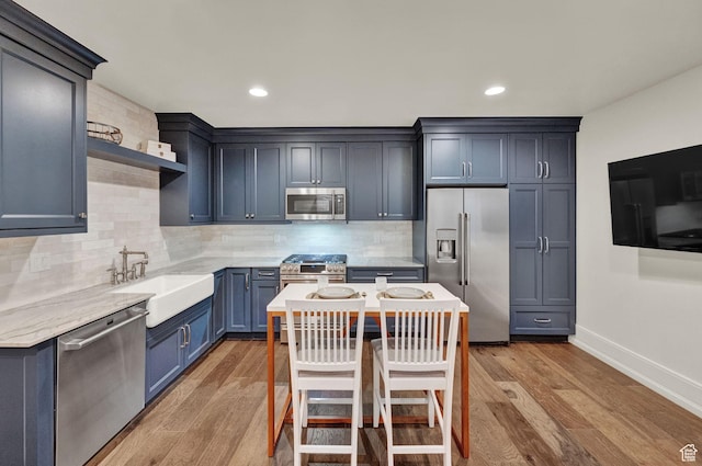 kitchen with tasteful backsplash, open shelves, appliances with stainless steel finishes, light wood finished floors, and a sink