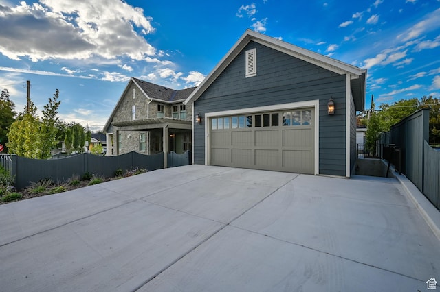 view of front facade featuring an attached garage, concrete driveway, and fence