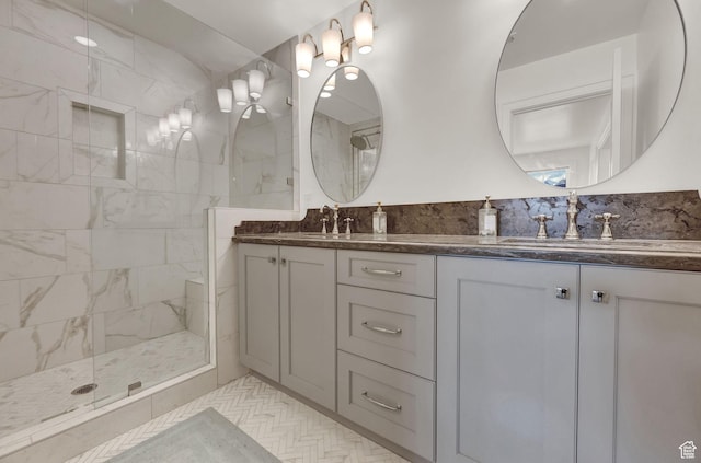 full bathroom with a sink, tiled shower, and double vanity