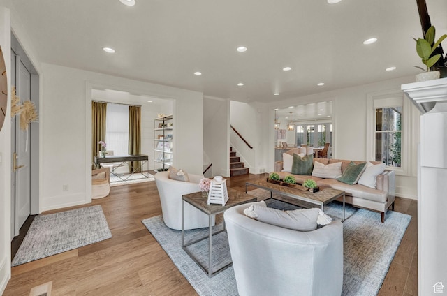 living room featuring light wood-style flooring, recessed lighting, and stairs