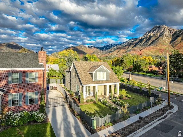 view of front of property featuring a mountain view, a chimney, concrete driveway, and a fenced front yard