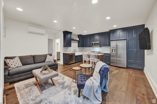 living area featuring baseboards, light wood-type flooring, recessed lighting, and a wall unit AC
